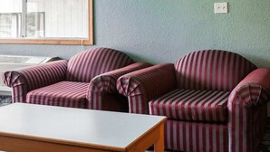 A room with two striped armchairs, a wooden table, and a window with blinds. - 2 Full Beds | Non-Smoking (Stevenson WA)