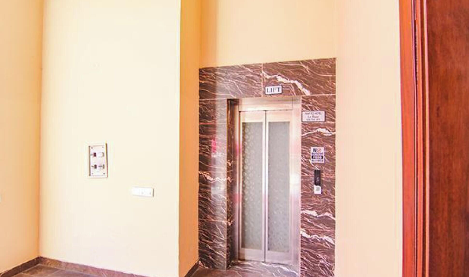 An elevator with marble detailing, a wall-mounted sign, and a door handle.