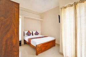 A bedroom with a wooden bed, white bedding, and a colorful throw. - Fabhotel Nimalan Residency Sholinganallur (Chennai)