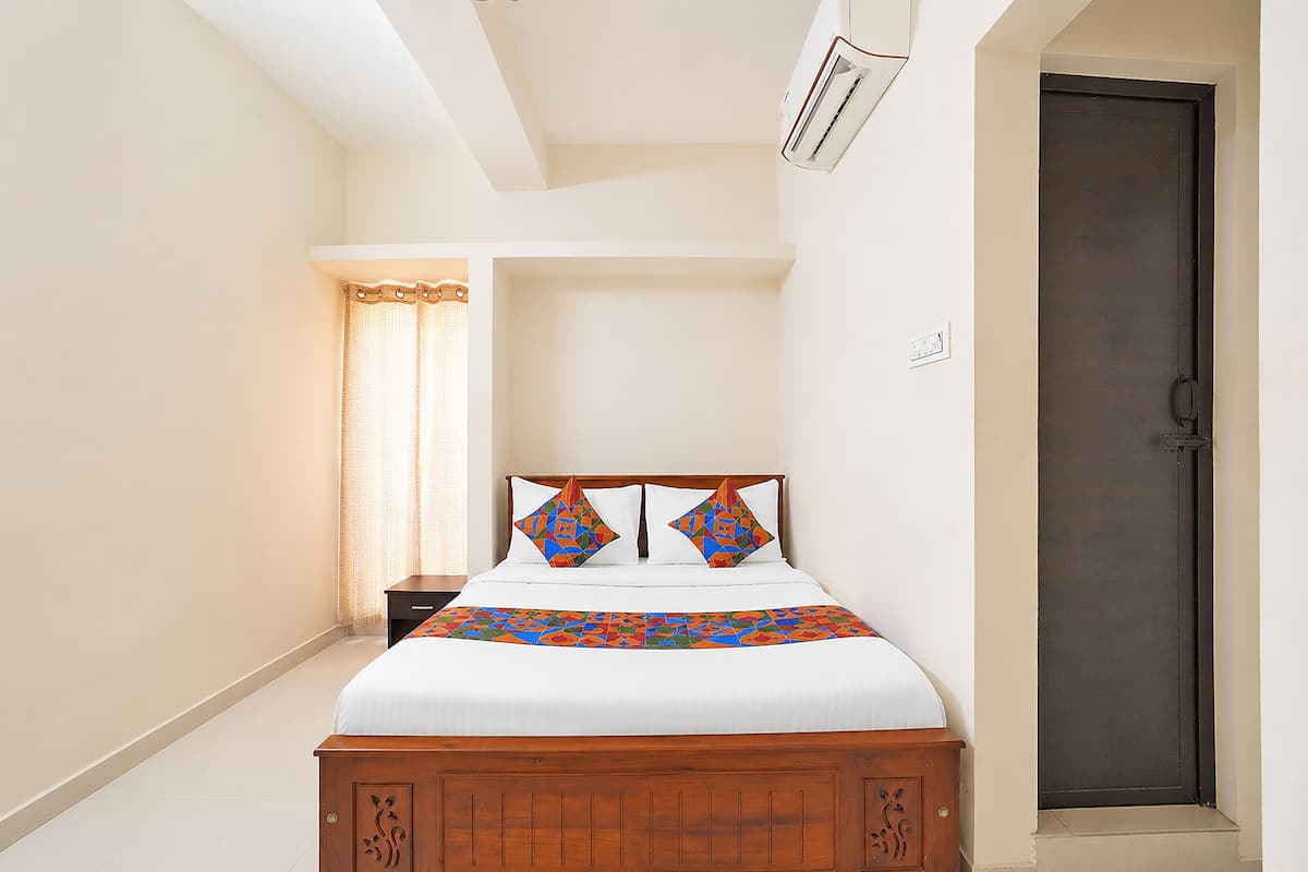 A bedroom with a wooden bed, a nightstand, a door, and a window with curtains.