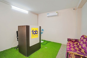 A room with a podium, a fan, an air conditioning unit, and a purple chair. - Fabhotel Nimalan Residency Sholinganallur (Chennai)