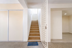 A staircase leading to a landing with a metal gate, a sliding door, and a patterned floor mat. - Fabhotel Nimalan Residency Sholinganallur (Chennai)