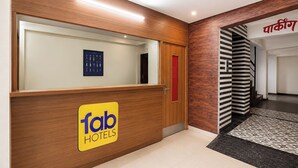 Una recepción con un cartel de 'fab hotels', un expositor de llaves enmarcado y una pared de madera.