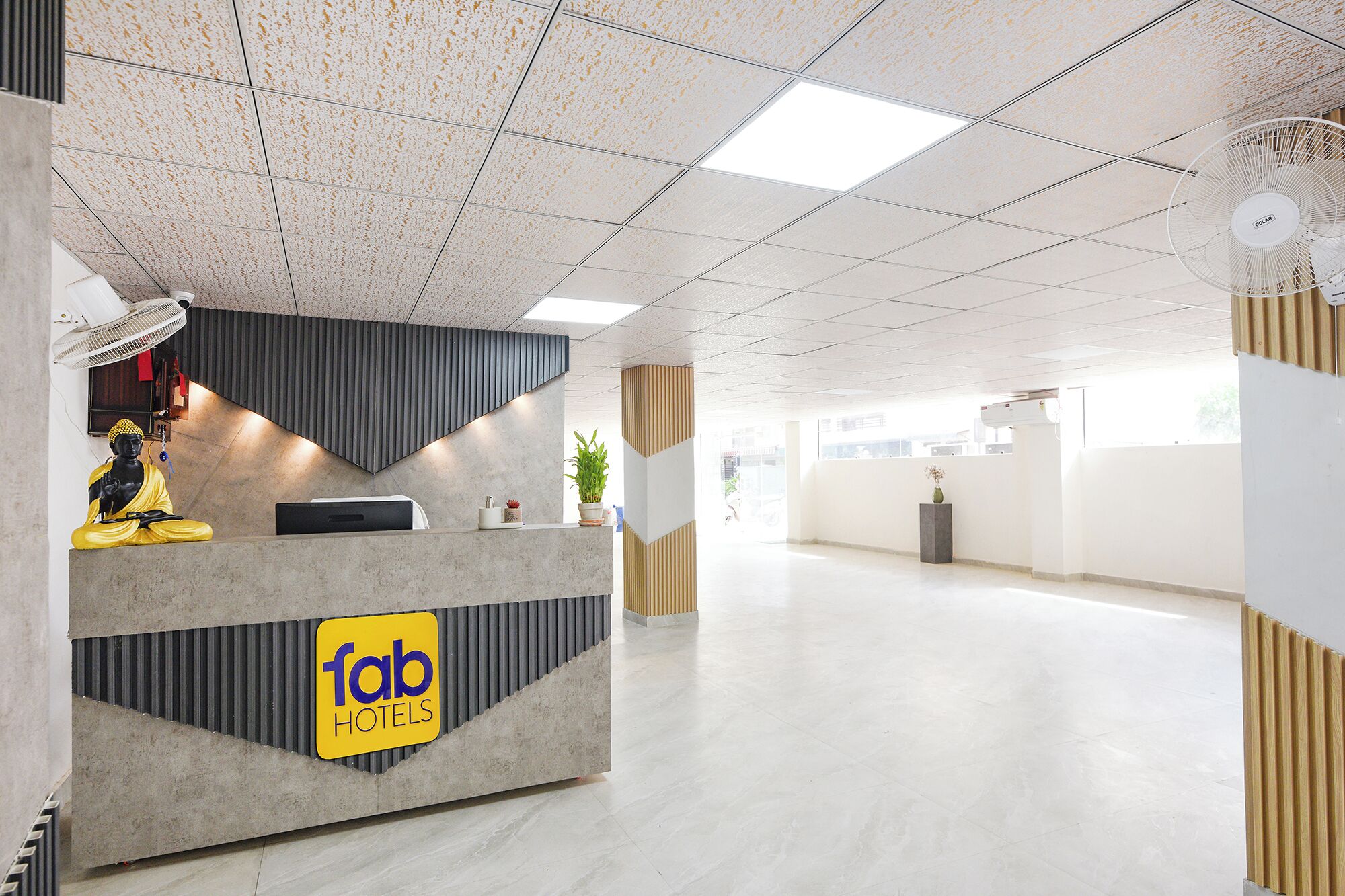 A hotel reception area with a modern design, a reception desk, and a statue.