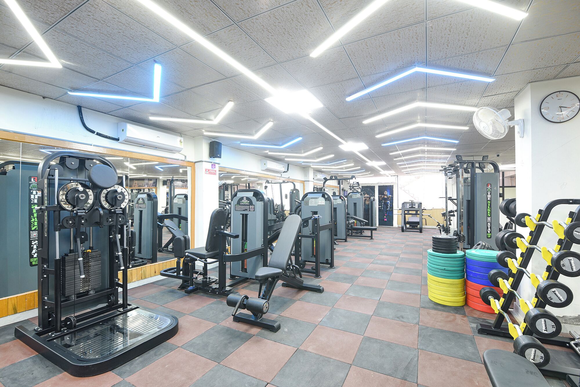 A gym with exercise equipment, a clock, and a tiled floor.