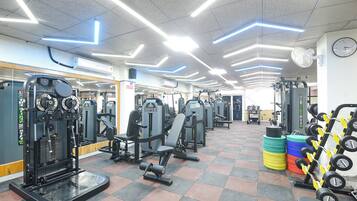 A gym with exercise equipment, a clock, and a tiled floor.
