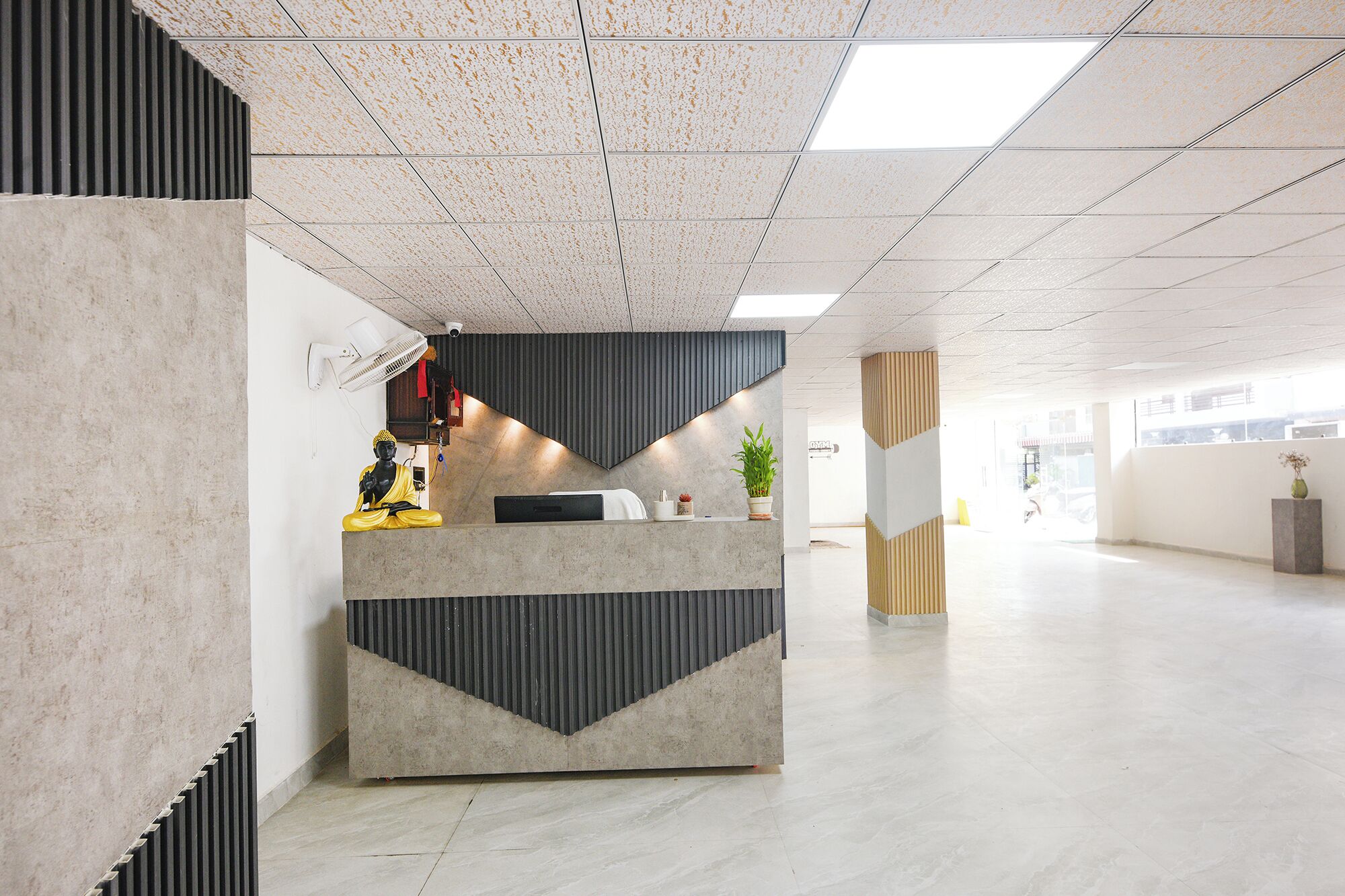 A reception desk with a modern design, a statue, and a potted plant.