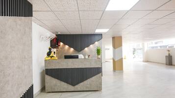 A reception desk with a modern design, a statue, and a potted plant.