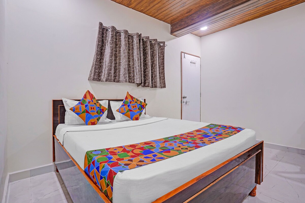 A bedroom with a bed, pillows, curtains, and a door.