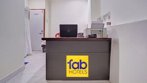 A hotel reception desk with a laptop, a telephone, and a fax machine.