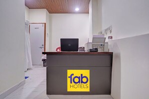 A hotel reception desk with a laptop, a telephone, and a fax machine.