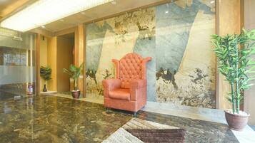 A lobby with a plush armchair, a marble floor, and a large wall with a map.