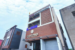 A hotel named 'Grand Plaza' with a sign indicating 'Tab Hotels' and 'Rooms, Restaurant, Rooftop'.
