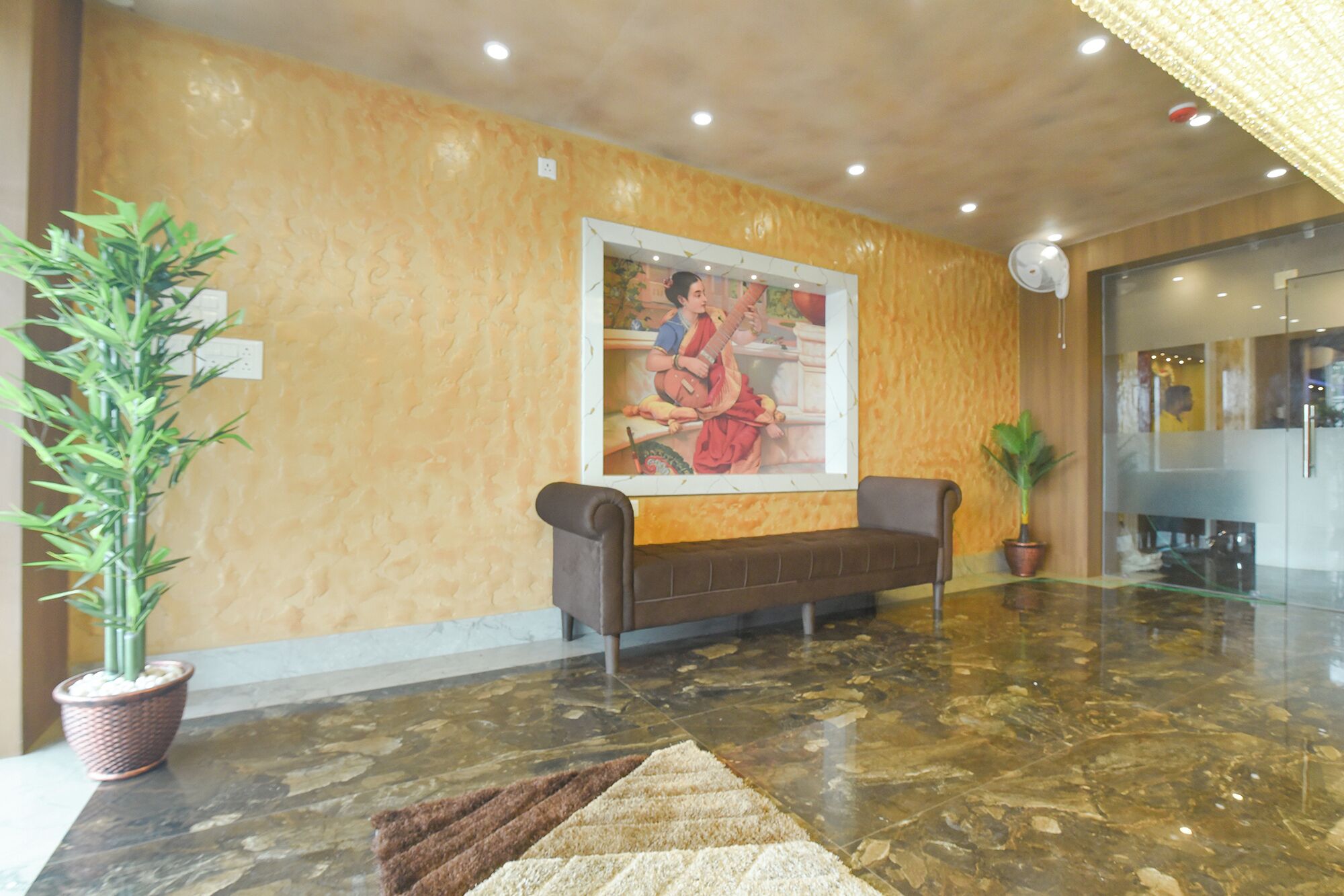 Un hall con suelo de mármol, un sofá, una planta en maceta y un cuadro colgado en la pared.