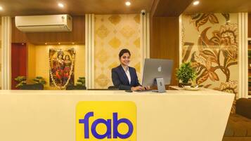 Ein Hotelrezeptionstresen mit einem Computer, eine Wand mit floralen Mustern und ein Schild mit der Aufschrift 'fab hotels'.