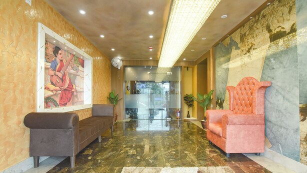 A lobby with a marble floor, a large mural, a sofa, a chair, and a fan. - Fabhotel Prime Grand Plaza (Barakpur)