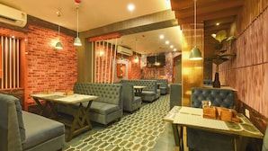 A restaurant interior with brick walls, blue upholstered seating, and patterned flooring. - Fabhotel Prime Grand Plaza (Barakpur)