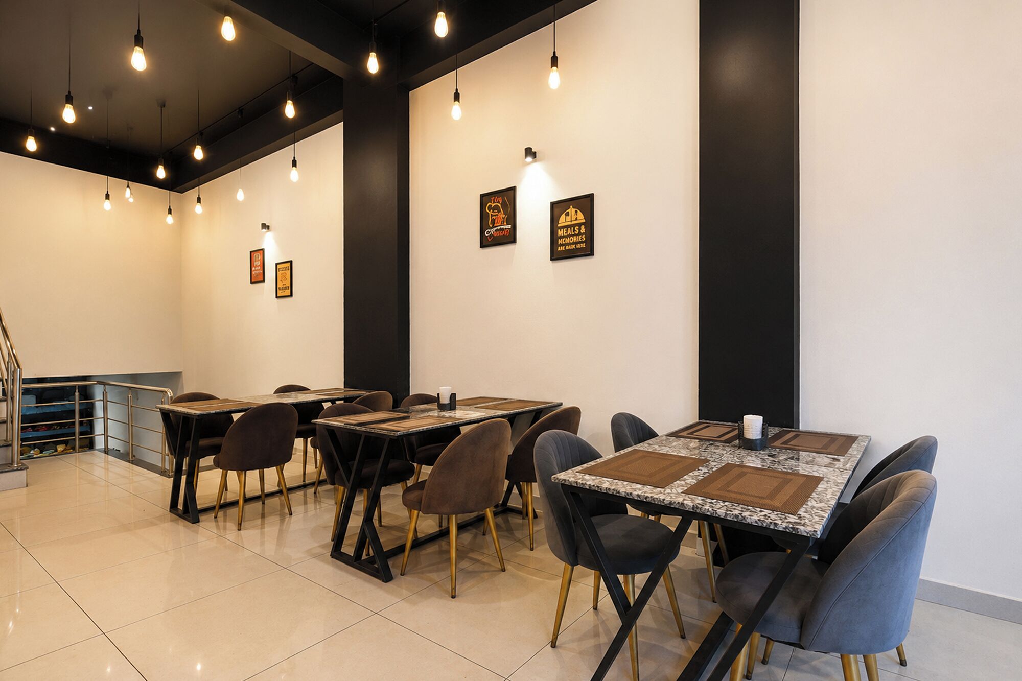 Un espace repas avec des tables et des chaises, un éclairage au plafond et des panneaux encadrés accrochés aux murs.