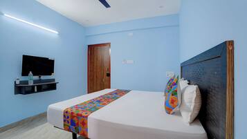 A bedroom with a bed, a television on the wall, a ceiling fan, and a wooden door.