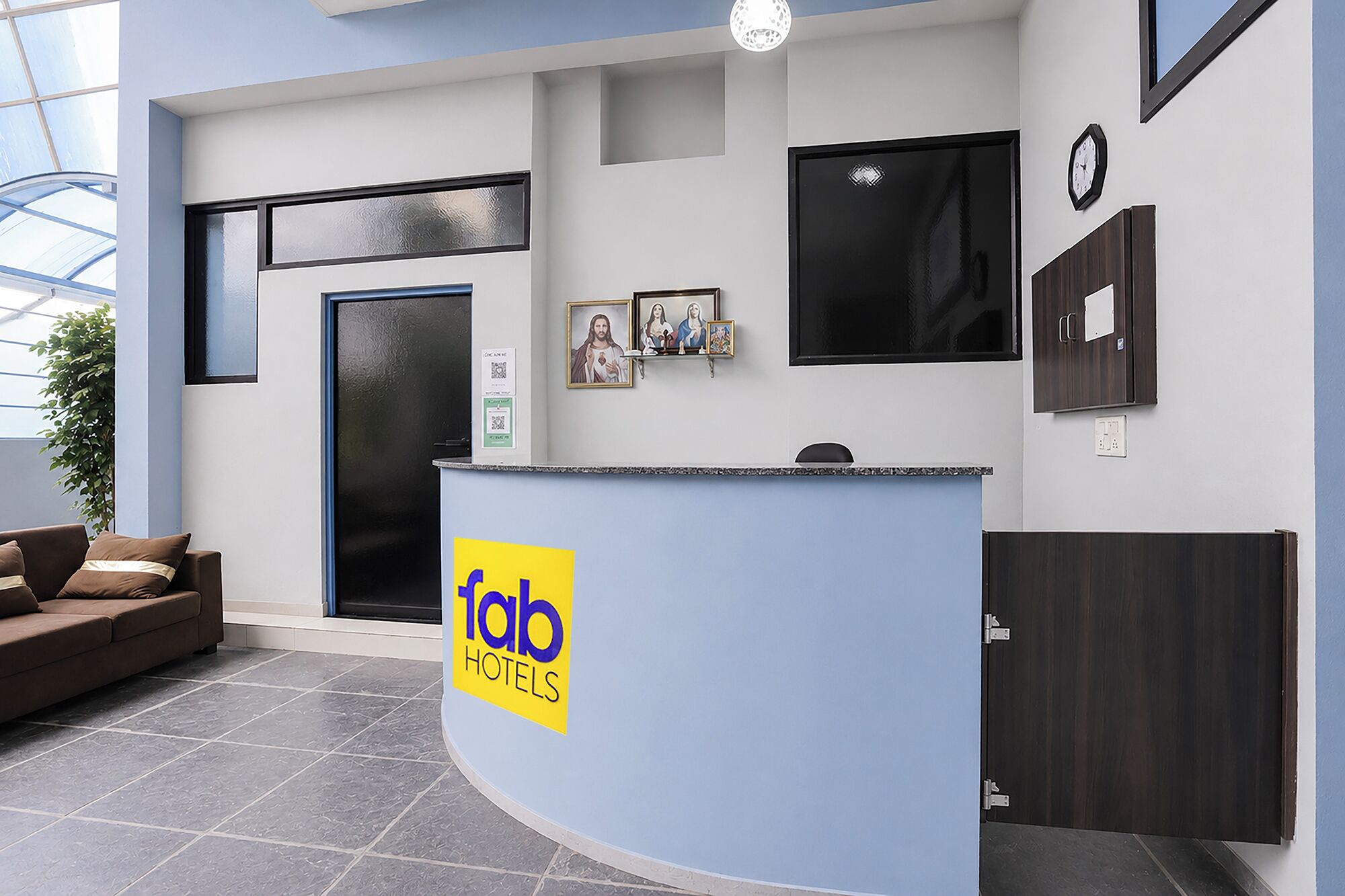 Zona de recepción de un hotel con un mostrador curvo, un reloj, cuadros enmarcados y un sofá.