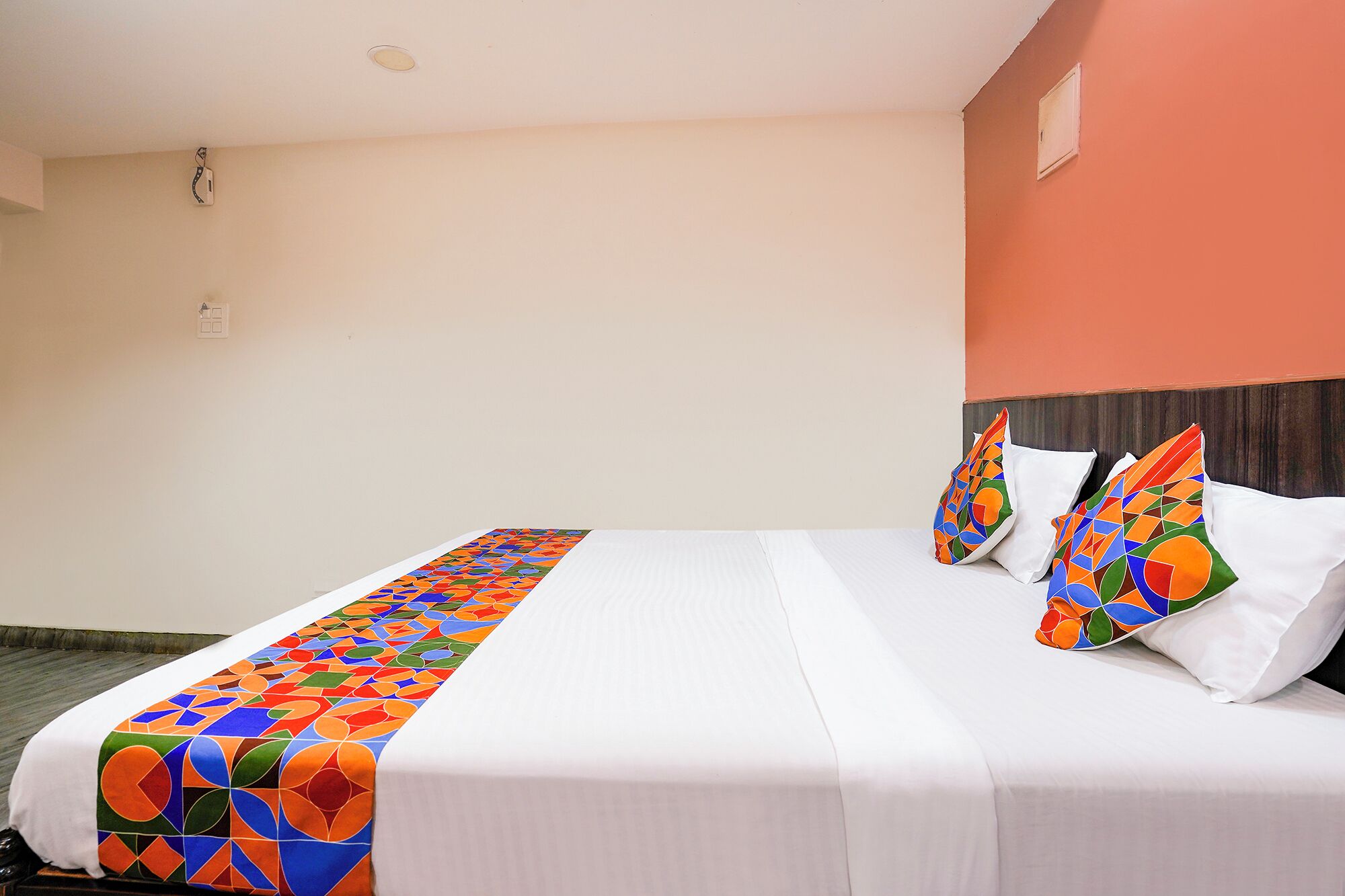 A hotel room with a bed, pillows, and a colorful headboard.