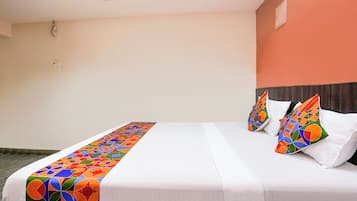 A hotel room with a bed, pillows, and a colorful headboard.
