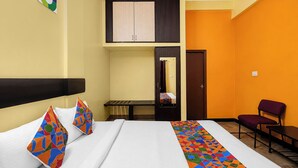 Une chambre d’hôtel avec un lit, une chaise, une petite table, un miroir et une porte.