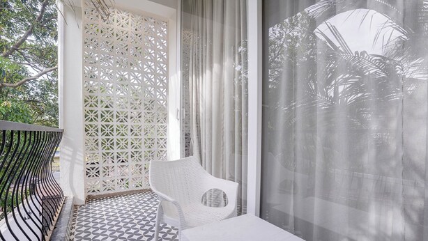 A balcony with a patterned floor, a white chair, and a table.