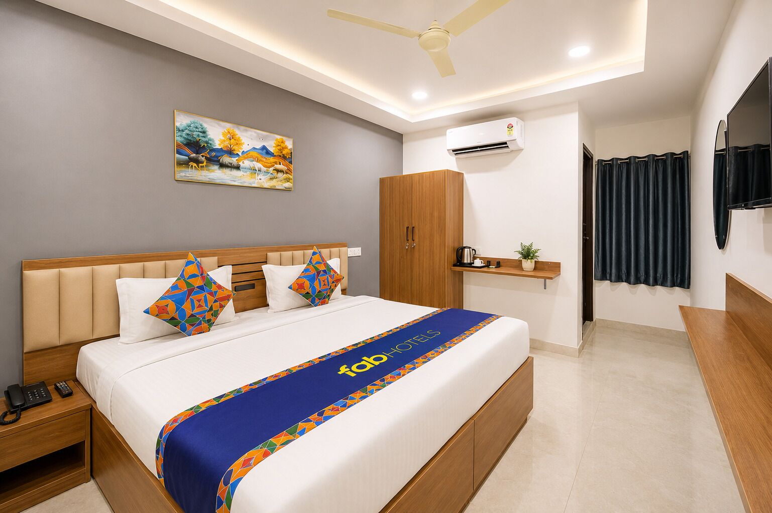 A hotel room with a bed, a nightstand, a wardrobe, an air conditioning unit, a television, and a painting on the wall.
