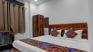 A bed with a geometric-patterned bedspread, a wooden headboard, and two pillows with a colorful geometric design. - FabHotel Platinum Pavillion Residency (Nashik)