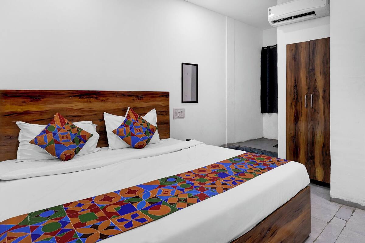 Uma cama com colcha estampada em padrão geométrico, cabeceira de madeira e duas almofadas com padrão semelhante.