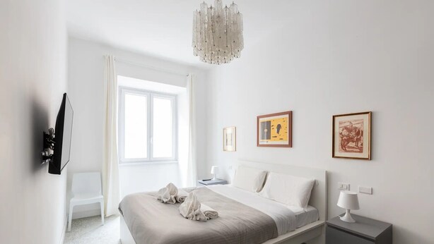 A modern bedroom with a bed, bedside tables, a chandelier, and artwork on the wall. - Room 'Stanza 2' with Wi-Fi and Air Conditioning (Rome)