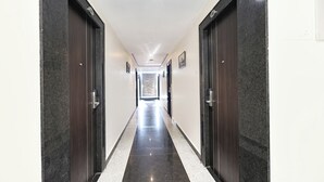 Un pasillo con puertas de madera oscura, paredes blancas y un suelo a rayas negras y blancas.