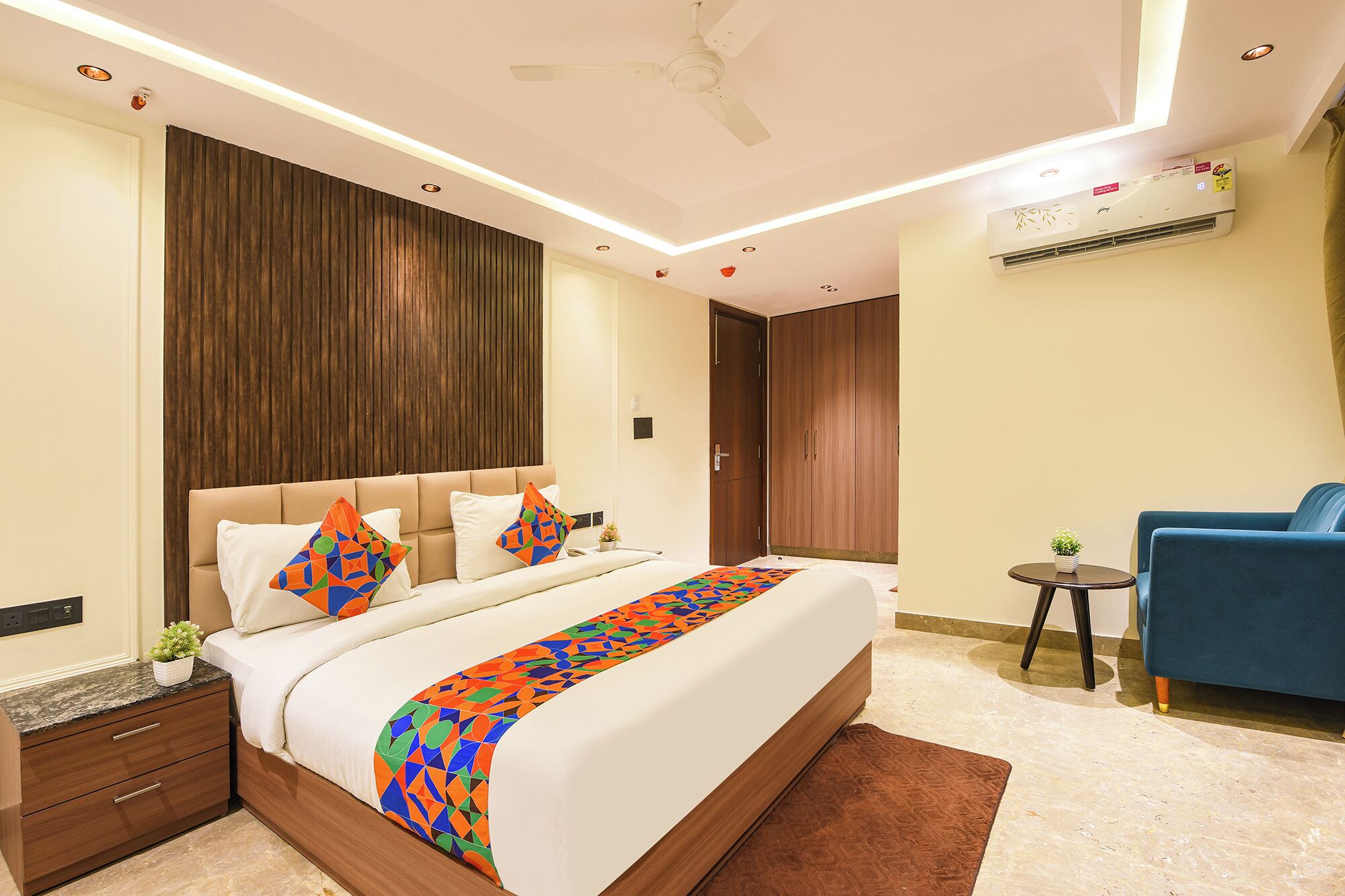 Una habitación de hotel moderna con cama, mesita de noche y una pequeña mesa redonda con una silla.