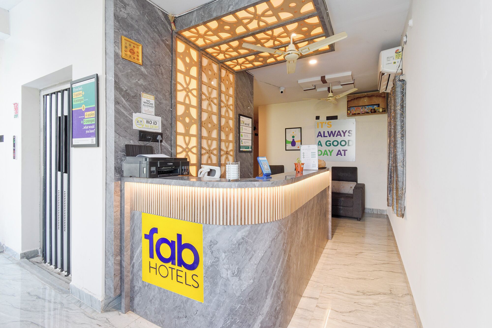 Una recepción de hotel con mostrador de mármol, un ventilador de techo y un letrero que dice 'fab hotels'.