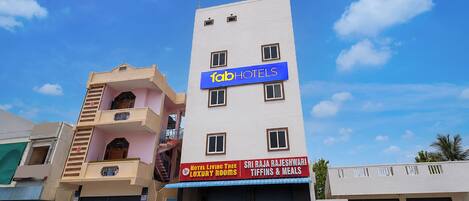 A multi-story hotel with a sign for 'fabHOTELS' and another sign for 'Sri Raja Rajeshwari Tiffins & Meals'.