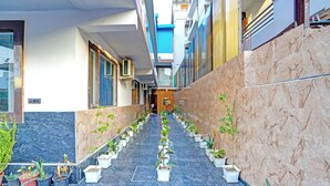 A corridor with potted plants, a marble floor, and a door at the end. - Fabhotel Pillow & Pesto (Noida)