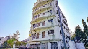 A multi-story building with balconies, a gated entrance, and a clear sky.