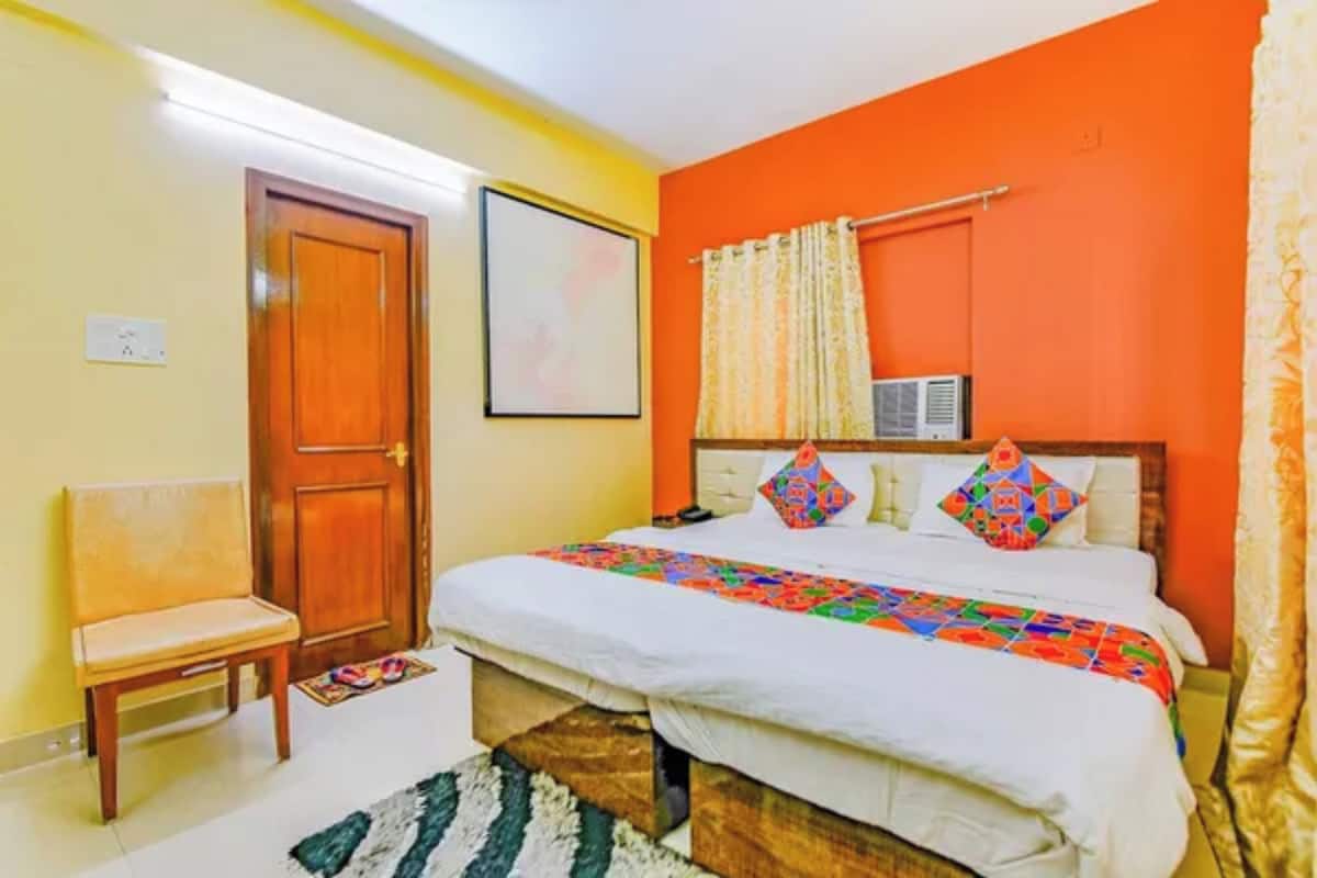 A bedroom with a bed, a chair, a door, and an air conditioning unit.