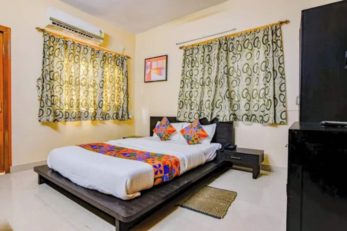A bedroom with a bed, a nightstand, a TV, and patterned curtains.