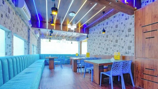 A restaurant with a long blue bench, wooden tables, and chairs.