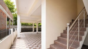 A covered outdoor area with a tiled floor, a staircase, and a brick wall.