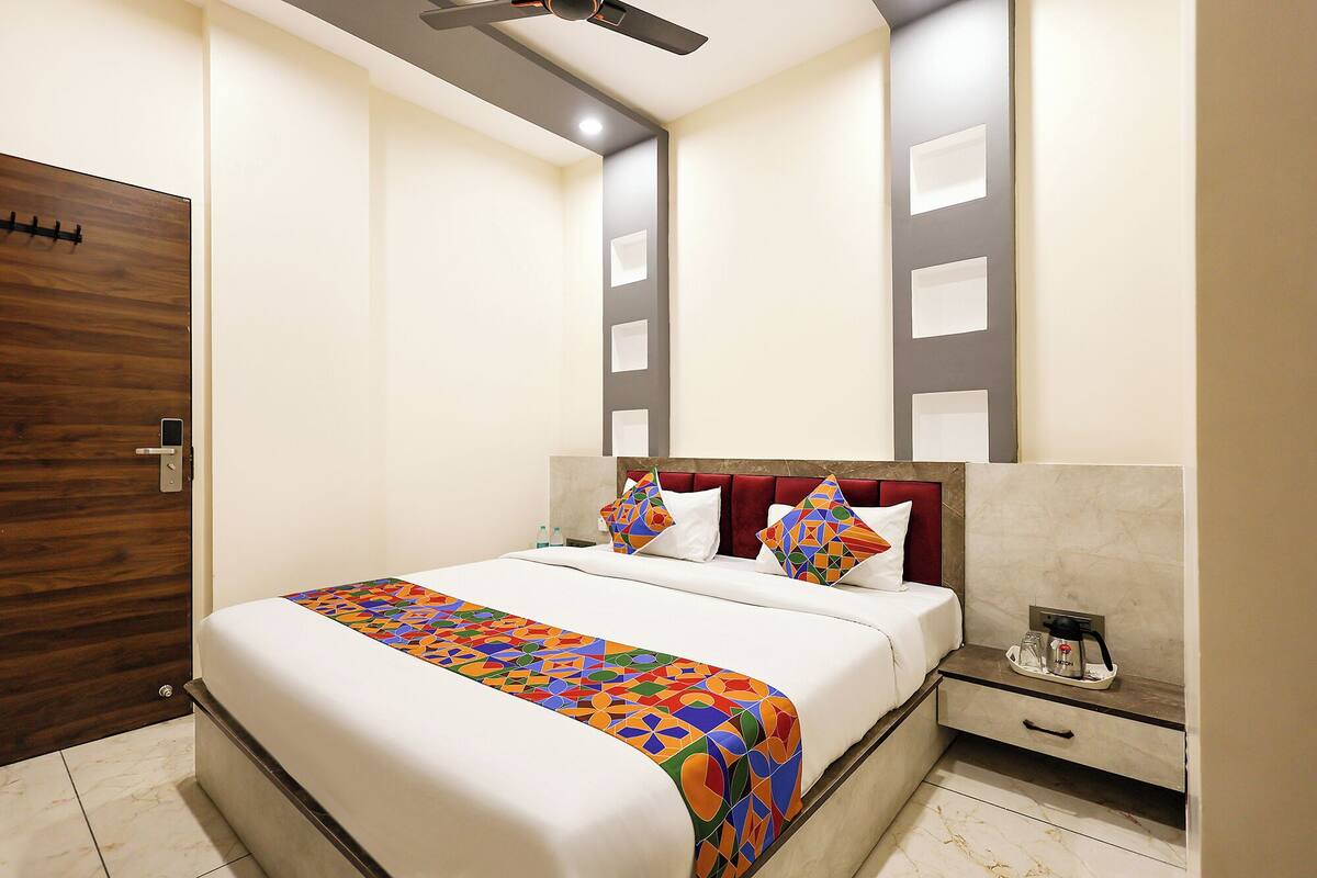 Quarto de hotel com cama, mesa de cabeceira, máquina de café e porta.