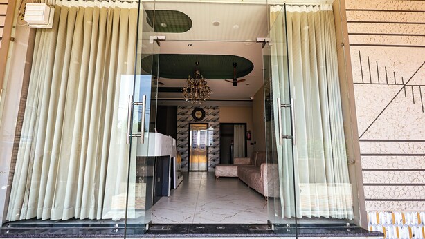 A hotel entrance with a glass door, a ceiling fan, a chandelier, and a view into the interior. - Fabhotel Prime Shyam Emprial (Khatoo)