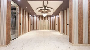 A spacious hallway with a modern design, featuring a marble floor and wooden paneling on the walls. - Fabhotel Prime Shyam Emprial (Khatoo)