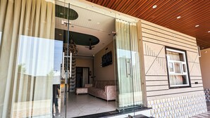 A modern interior with a glass door entrance, a living area with a sofa, and a patterned wall. - Fabhotel Prime Shyam Emprial (Khatoo)