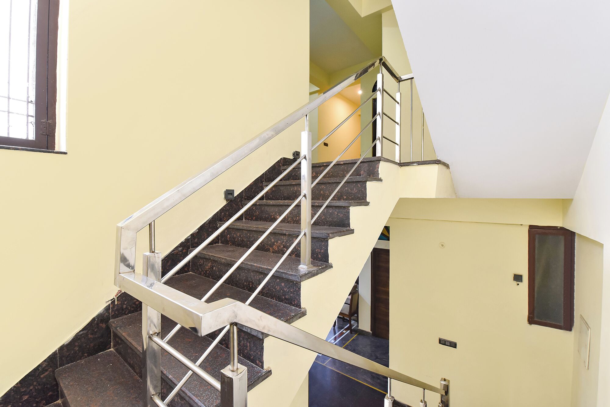 Un interior de varios niveles con una escalera, barandillas y una puerta con interruptor de luz.