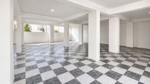 Una habitación amplia con suelo de cuadros, paredes blancas y ventanas grandes.
