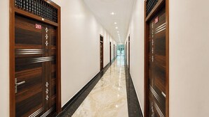 Passadís llarg i estret amb portes de fusta a ambdós costats, numerades 207 i 206, que condueix a una habitació lluminosa al final.