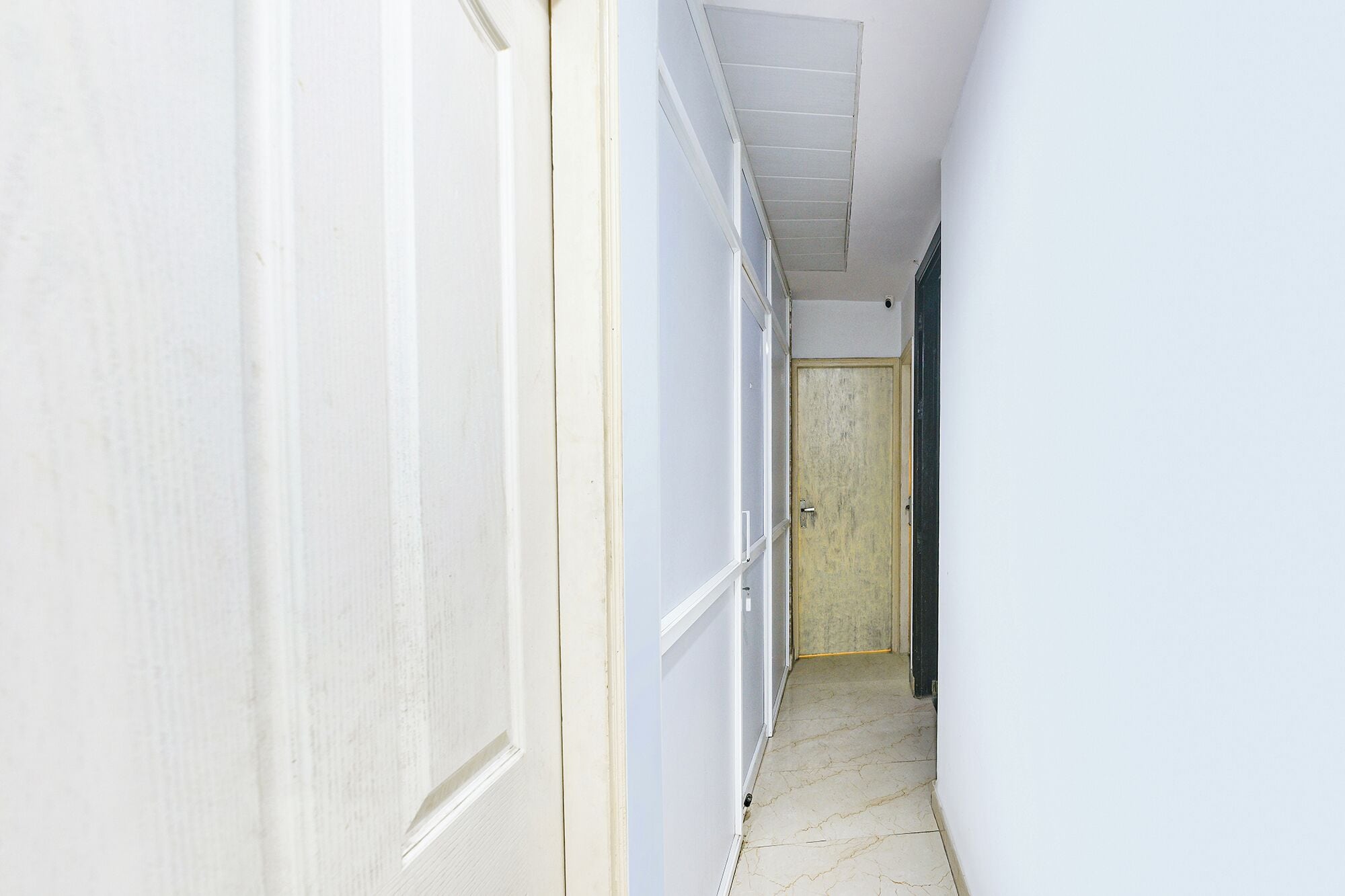 A narrow hallway with white walls and a door at the end.